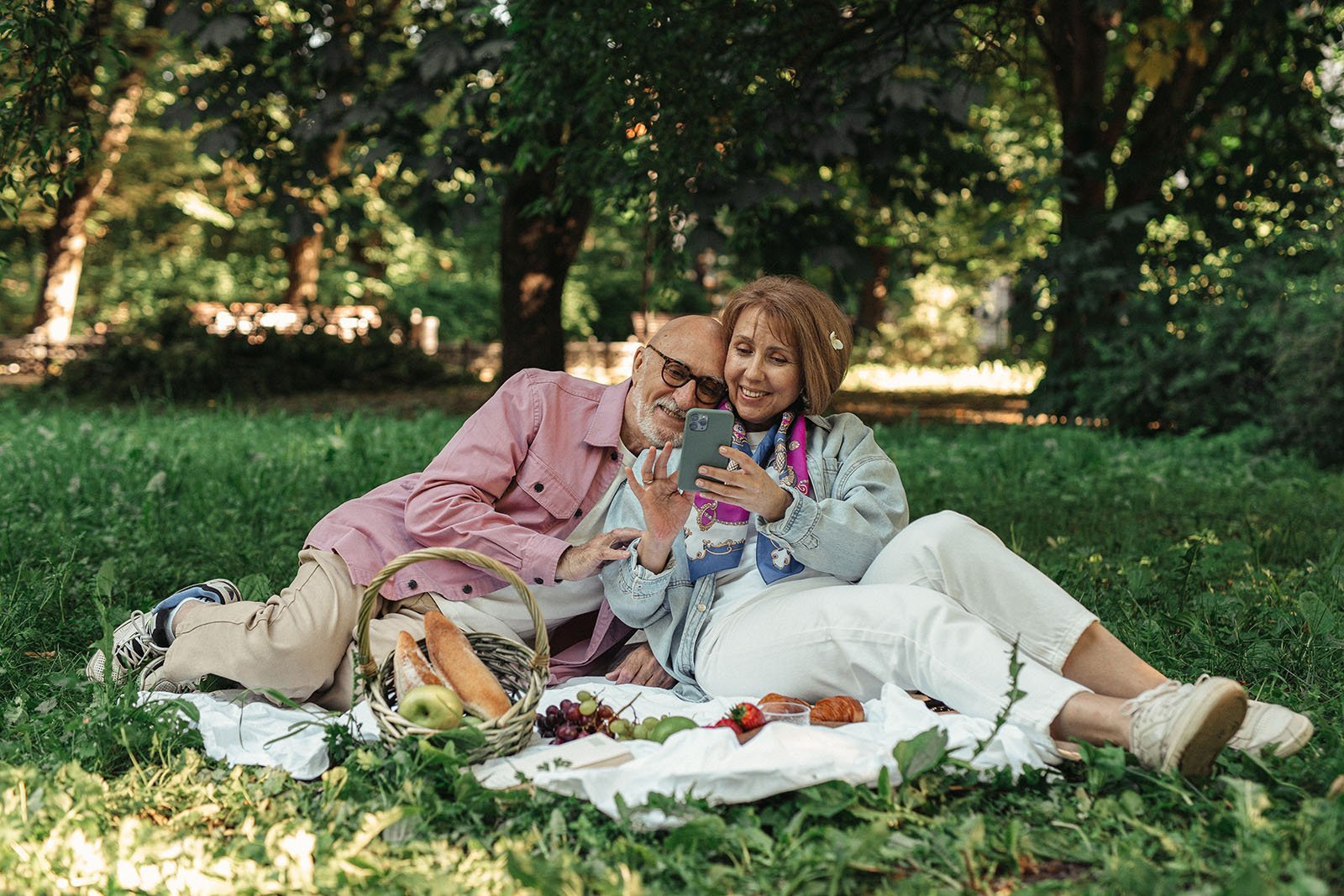 Elderly couple sitting in park looking at cellphone