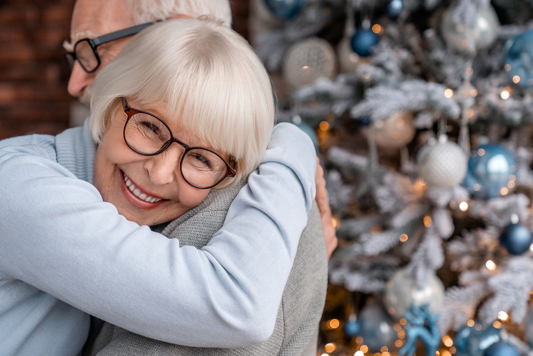 Senior couple hugging in front of Christmas tree